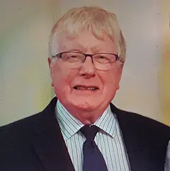 Elderly man in suit and glasses smiling