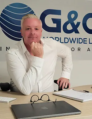 Man in white shirt at desk with laptop.